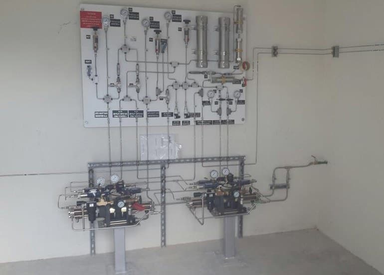 Booster station control panel above two air-driven gas boosters on stands
