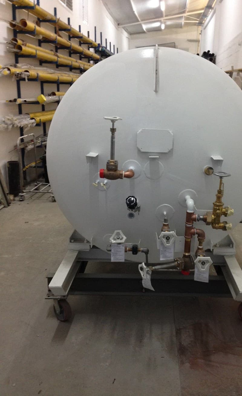 A horizontal pressure vessel on a trolley, with brass and copper valving