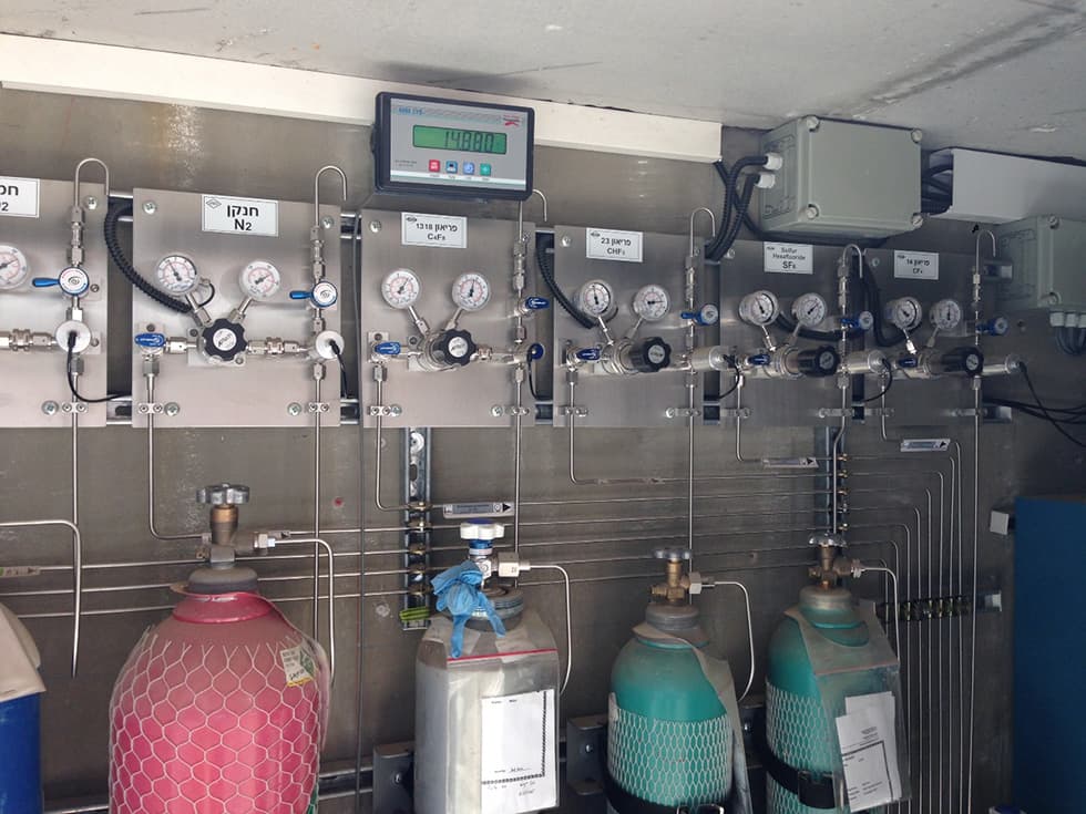 Wall of specialty-gas panels with Hebrew labelling and cylinders