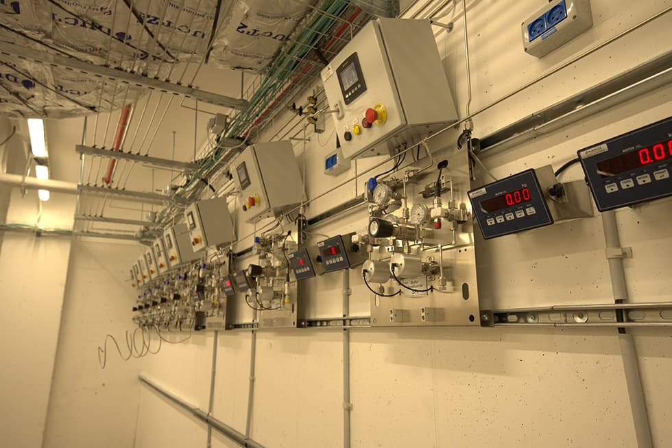 A long row of gas panels with digital weighing displays along a gas room