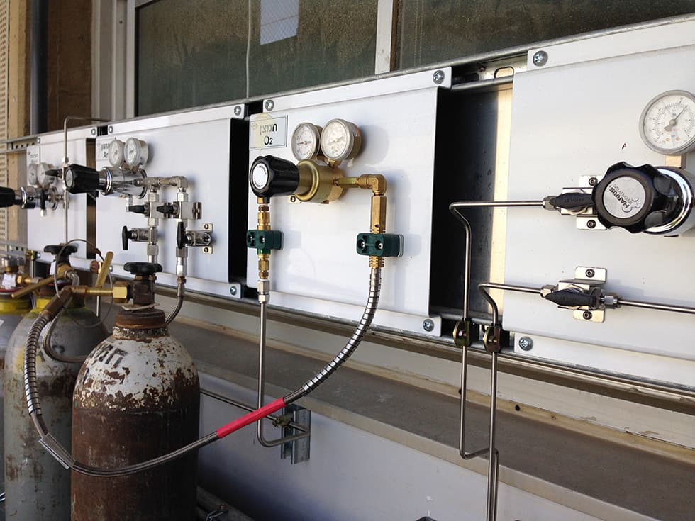 Gas panel along a window with regulators, gauges and a connected cylinder