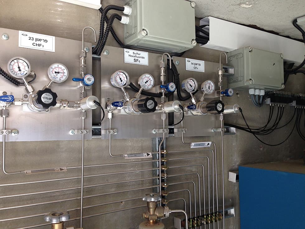 A row of stainless panels with Hebrew gas labelling and cable trays above