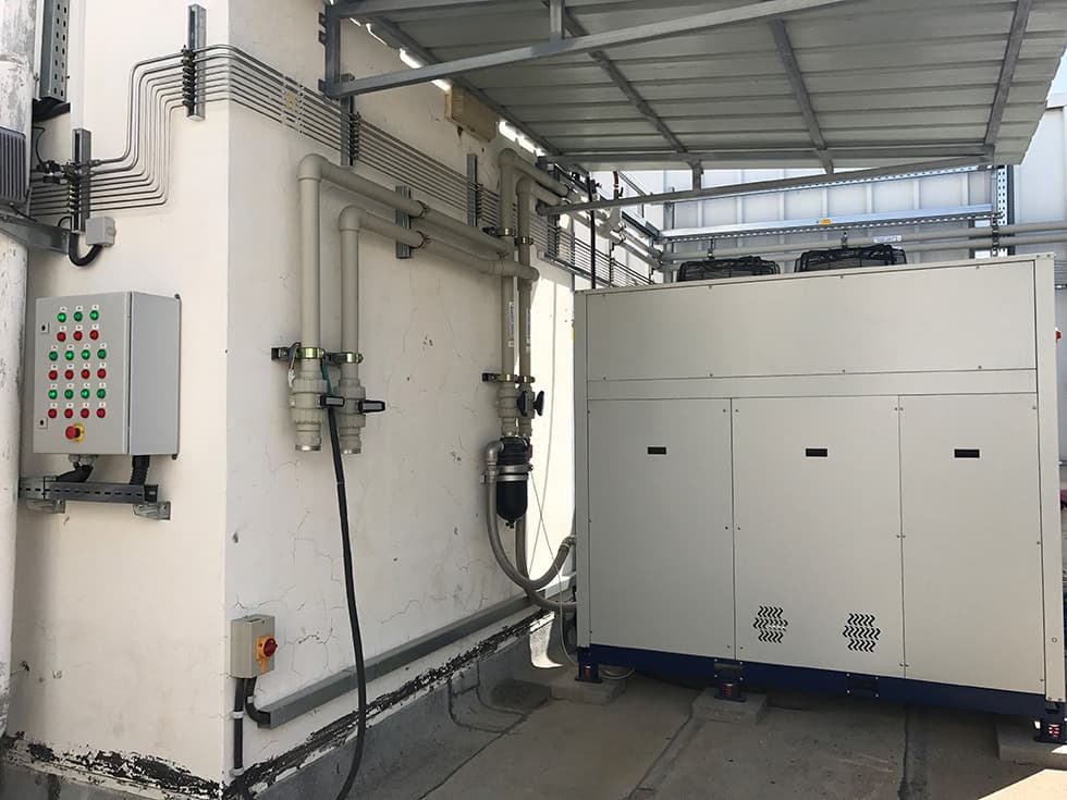 Outdoor equipment area with a chiller, control cabinet and pipe runs