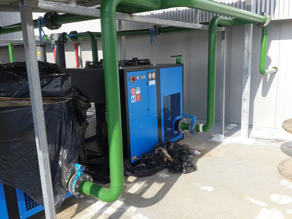 Compressor room with a screw compressor and green pipework