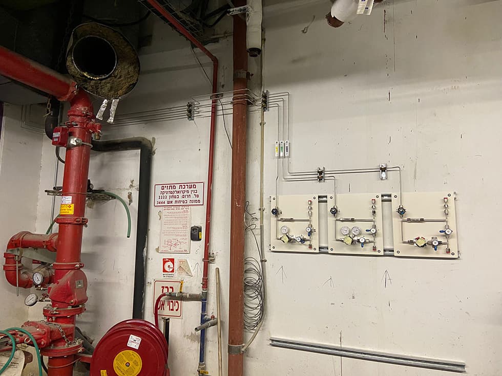 Red fire-fighting main with a hose reel, beside a gas panel