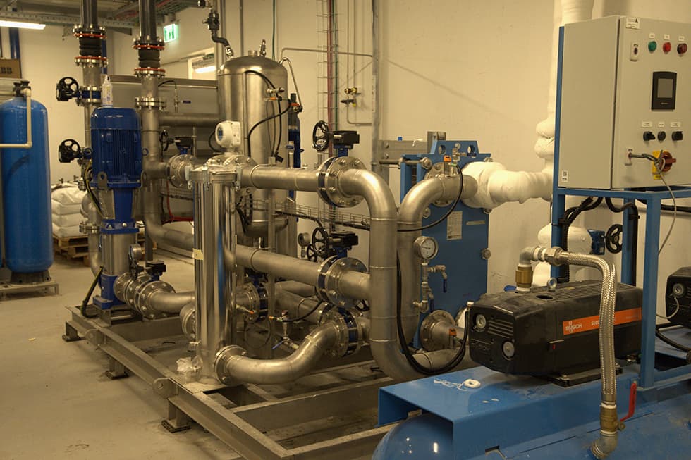 A stainless piping skid with vertical pumps and a plate heat exchanger