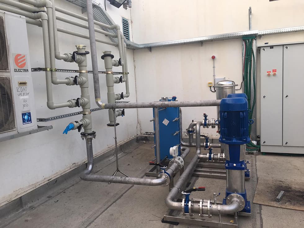 A pump and heat-exchanger skid installed outdoors beside an electrical cabinet