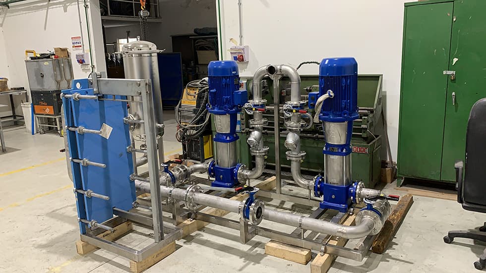 A pump and heat-exchanger skid assembled on pallets in the workshop